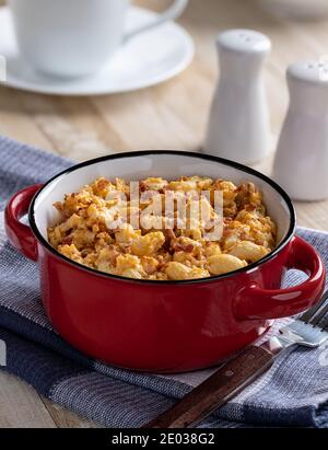 Bowl of macaroni and cheese with bacon pieces on a wooden table