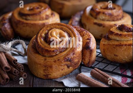 Closeup of fresh cinnamon rolls on a cooling rack with cinnamon sticks Stock Photo