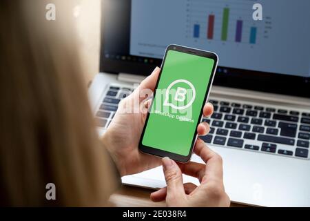 ROSARIO, ARGENTINA - DECEMBER 29, 2020: Whatsapp Business app logo on screen of mobile phone holder for a hands of young woman. Smartphone with green Stock Photo