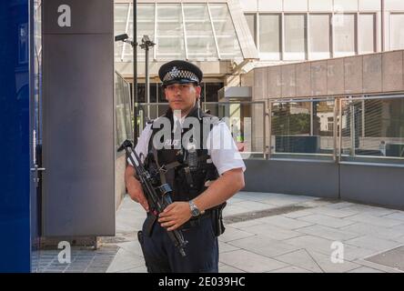 An armed Metropolitan Police Officer on duty outside New Scotland Yard in London, England, UK Stock Photo