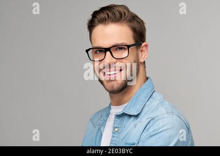 Portrait of young handsome caucasian man in jeans shirt over light background Stock Photo