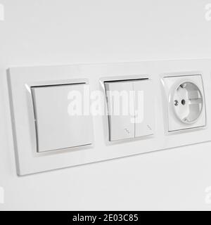 White plastic walk-through switches and sockets on a white wall Stock Photo