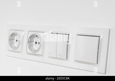 White plastic walk-through switches and sockets on a white wall Stock Photo