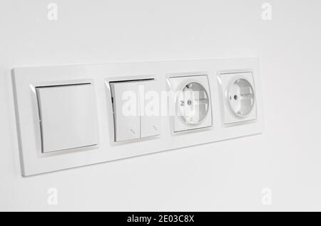 White plastic walk-through switches and sockets on a white wall Stock Photo