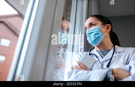 Female doctor looking out the hospital window Stock Photo