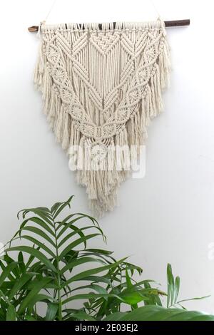 Green plant, knitted tapestries hanging on wall, bohemian interior decoration Stock Photo