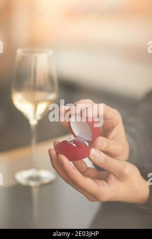 Close-up of man opening the box with engaged ring and making proposal to his woman in the restaurant Stock Photo