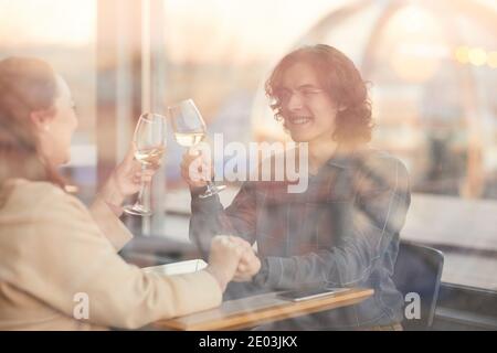 Young couple sitting at the table in the restaurant with glasses of champagne and celebrating their anniversary Stock Photo
