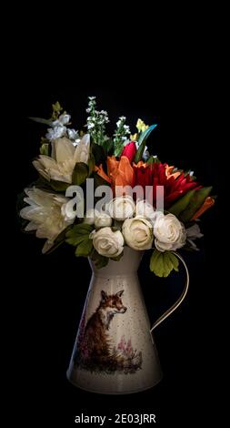 Bouquet of autumn orange and white flowers in a jug isolated against a black background. Stock Photo