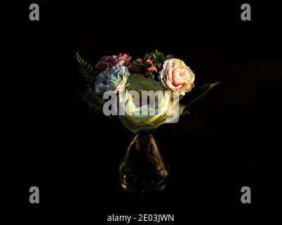 Bouquet of spring pink and white flowers in a glass vase isolated against a black background. Stock Photo