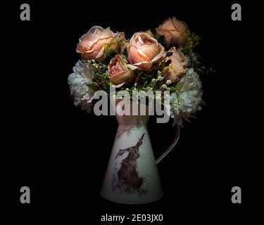 Bouquet of spring peach and white flowers in a jug isolated against a black background. Stock Photo