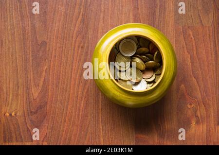 Small green wooden jar with Euro coins on a brown wooden background from above Stock Photo