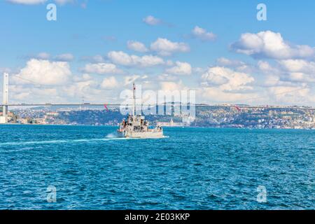 Naval vessel passing though Bosphorus  Bridge with background of Bosphorus strait on a sunny day with background cloudy blue sky and blue sea in Istan Stock Photo