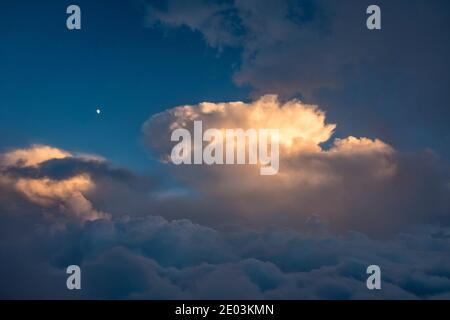A gibbous moon above dramatic cumulus clouds, seen from high in the Dolomites, northern Italy Stock Photo