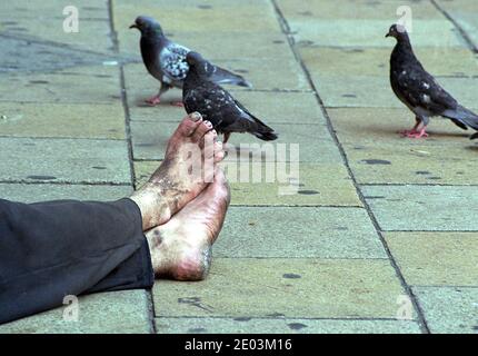 Rich poor divide inequality, dirty feet of Homeless person amongst pigeons Central London Stock Photo