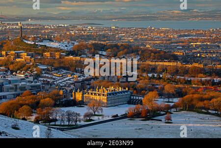 Edinburgh, Scotland, UK. 29 December 2020. Perfect winter's day, starting off with a cover of snow over the city allowing people to enjoy the outdoors and concluding with a beautiful warm sunset to end the day. Pictured: Holyrood Park with Holyrood Palace in mid ground, looking towards Calton Hill and the coast of Fife in the distance. Credit: Arch White/Alamy Live News. Stock Photo