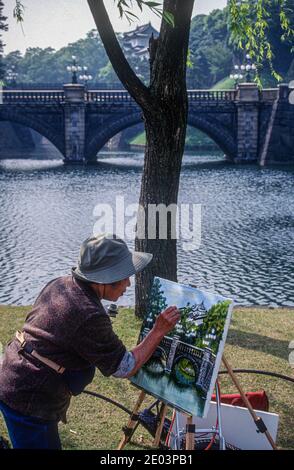 Japanese artist at work pianting the Seimon Ishibashi bridge, which forms the main entrance over the moat, to the Imperial Palace, Tokyo, Japan, May 1998 Stock Photo