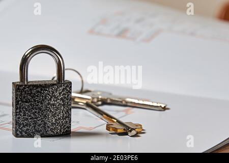 Metallic lock, keys and layout draft on apartment sale deal. Real estate concepts and symbols Stock Photo