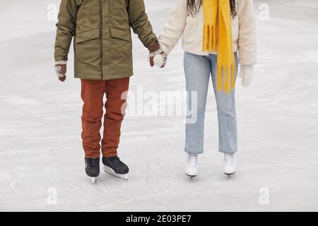 Close-up of couple in warm clothing standing on skating rink and holding hands Stock Photo