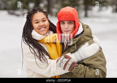Portrait of young multiethnic couple embracing each other and smiling at camera standing outdoors Stock Photo