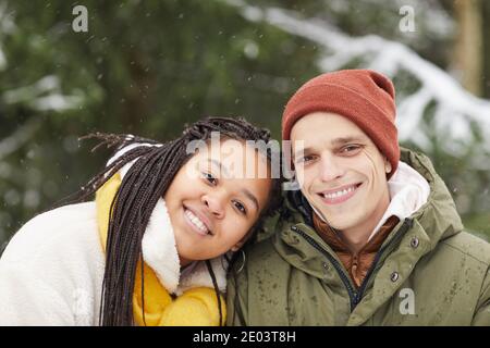 Winter portrait of multiethnic young couple smiling at camera outdoors Stock Photo