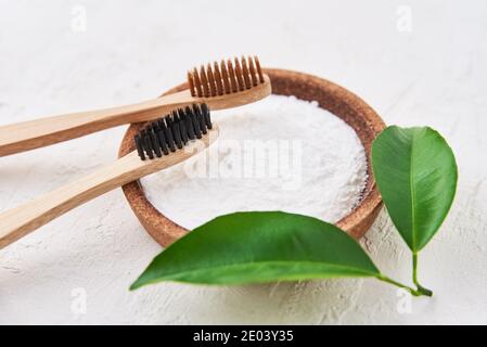 Two wooden bamboo toothbrushes and baking soda on a white background. Eco friendly toothbrushes, zero waste concept Stock Photo