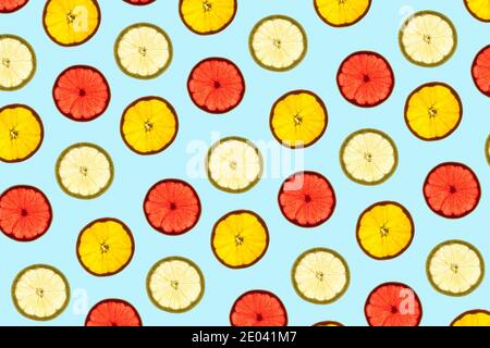 Pattern made of backlit citrus fruits slices on blue background Stock Photo