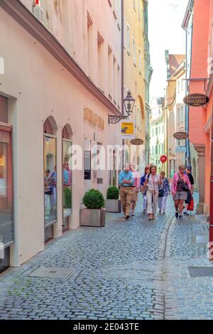 Intense building colors cast a rainbow on tourists in Regensburg's Old Town, Bavaria, Germany. Stock Photo