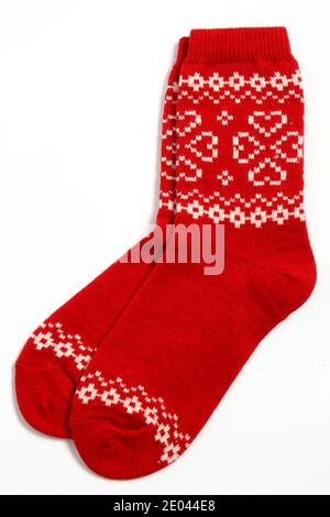 A pair of warm woolen winter socks with knitted white decorations, hearts isolated on white background. Socks for Christmas, holiday time or cold Stock Photo