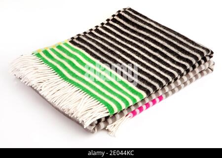 Warm colorful striper alpaca wool or cashmere blanket isolated on white background. Green, brown, black and pink color striped wool fabric for house Stock Photo