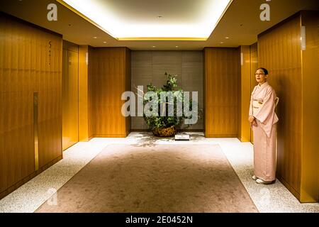 Elevator Receptionist of the Okura Hotel in Tokyo, Minato, Japan. Guardian of the elevators - a service in kimono that has been around since the 1960s. From the lobby, the elevators rise. From floor 28, the guest rooms begin in the Okura Prestige Tower Stock Photo