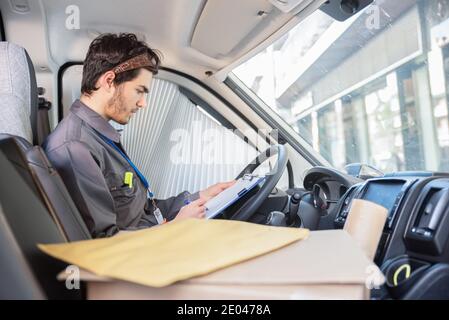 Courier in the van organising orders for delivery Stock Photo