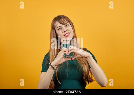 Hands shows the symbol of heart. Love to our pancreas. Pretty romantic young making a soul gesture with fingers in front chest showing feelings, affection happy tender smile. Stock Photo