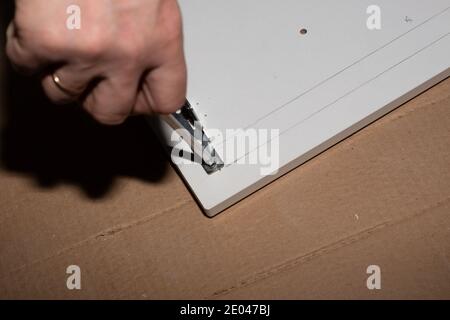 assembly of wooden furniture, screwing a screw with a screwdriver into the cabinet door. Carpenter services. Stock Photo