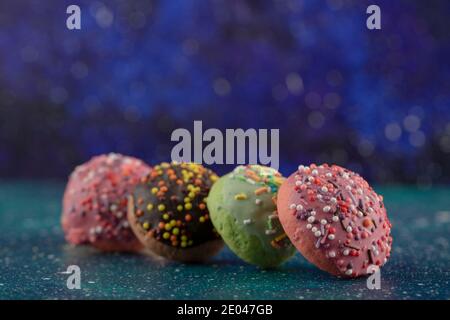 Colorful small doughnuts with sprinkles on a blue background Stock Photo