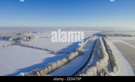 Winter road along the fields between cities aerial view from a drone. Winter landscape from a drone. Winter road view from a drone Stock Photo