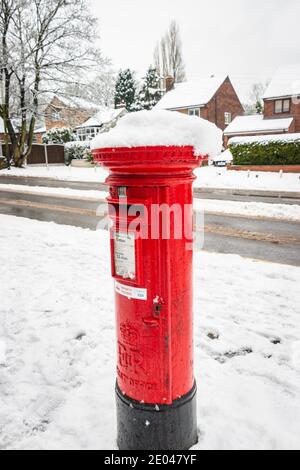 red Royal Mail UK post box in snowy street scene Stock Photo