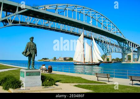 The Tall Ship Highlander sails under the Blue Water International Bridge on St. Clair River between Port Huron Michigan and Sarnia Ontario Canada Stock Photo
