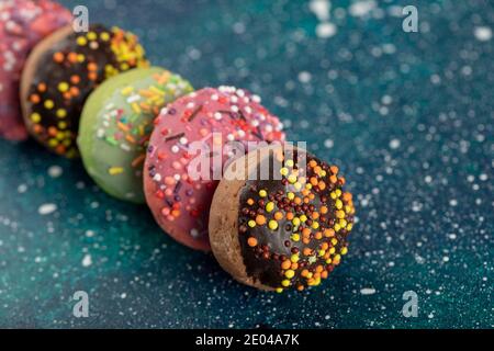 Colorful small doughnuts with sprinkles on a blue background Stock Photo