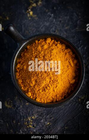 Turmeric powder and fresh turmeric on dark background. Stock Photo