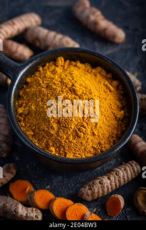 Turmeric powder and fresh turmeric on dark background. Stock Photo