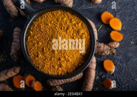 Turmeric powder and fresh turmeric on dark background. Stock Photo