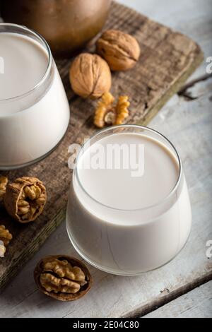 Organic walnut nuts and glass of walnut milk on wooden background. Stock Photo