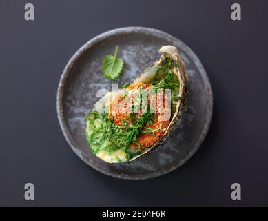 baked oyster with toasted bread and greens on grey plate, top view, selective focus Stock Photo