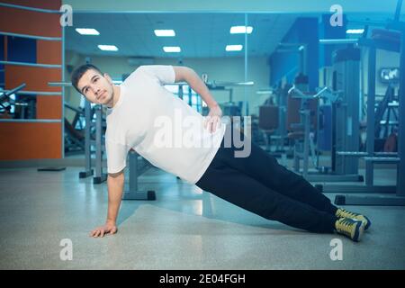 athletic male or bodybuilder has personal workout and planking in gym Stock Photo