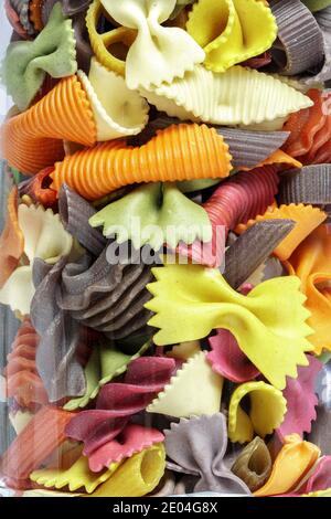 Different colored pasta in a glass, closeup, In the background a wonderful bokeh of orange lights Stock Photo