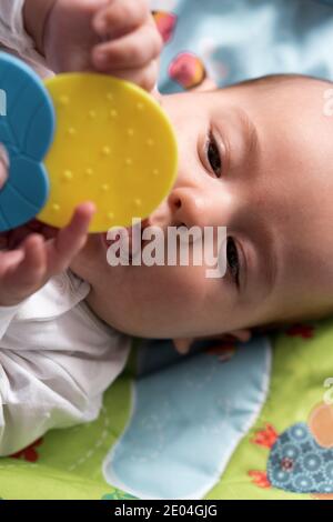 Childhood, happiness, motherhood concepts - Infant surprised, funny newborn child baby aged 3-4 months playing with toys, gnawing toothpicks on Stock Photo