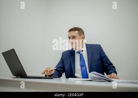 Young businessman working with documents looking through papers in folder, sitting at office desk Stock Photo