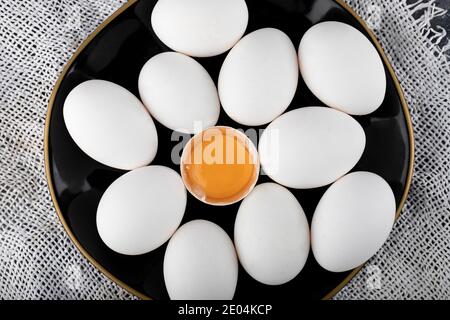 White eggs and yolk on black plate Stock Photo