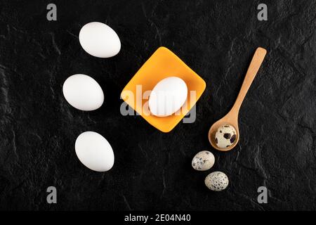 Quail eggs and chicken eggs on black background Stock Photo